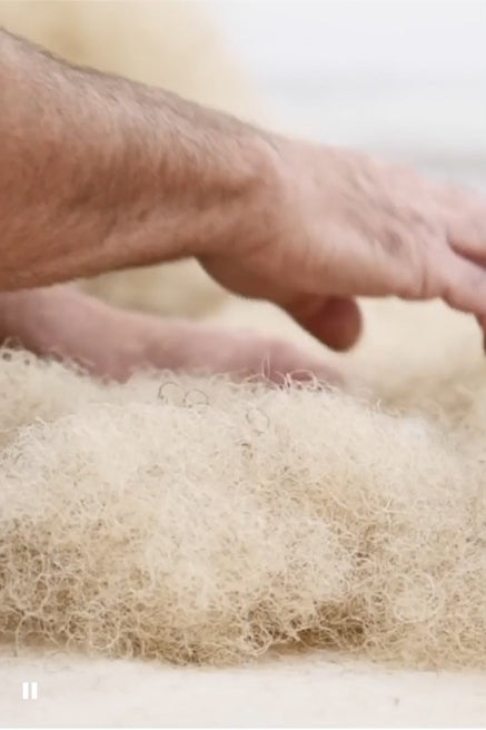 A Savoir craftsman laying horse hair on a mattress
