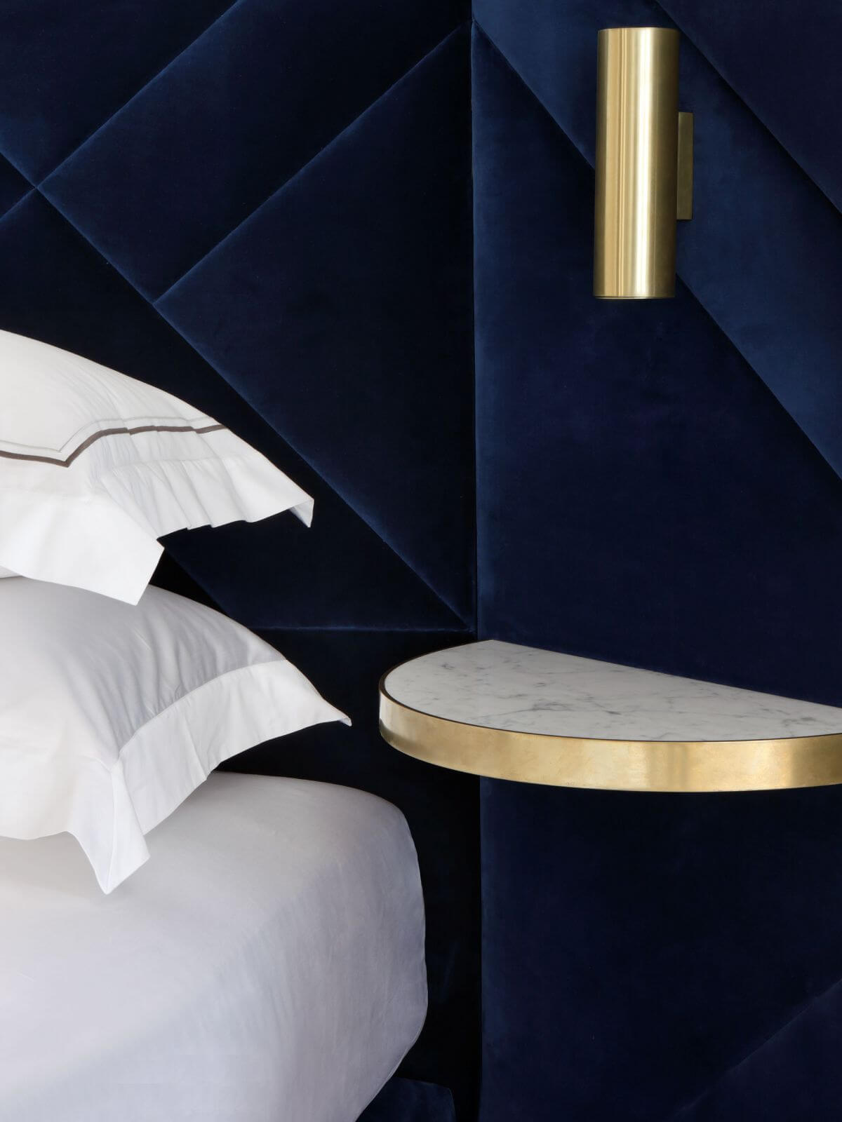 A close-up of the Rocco design, upholstered in decadent deep blue velvet, with brass gold details and marble finishes