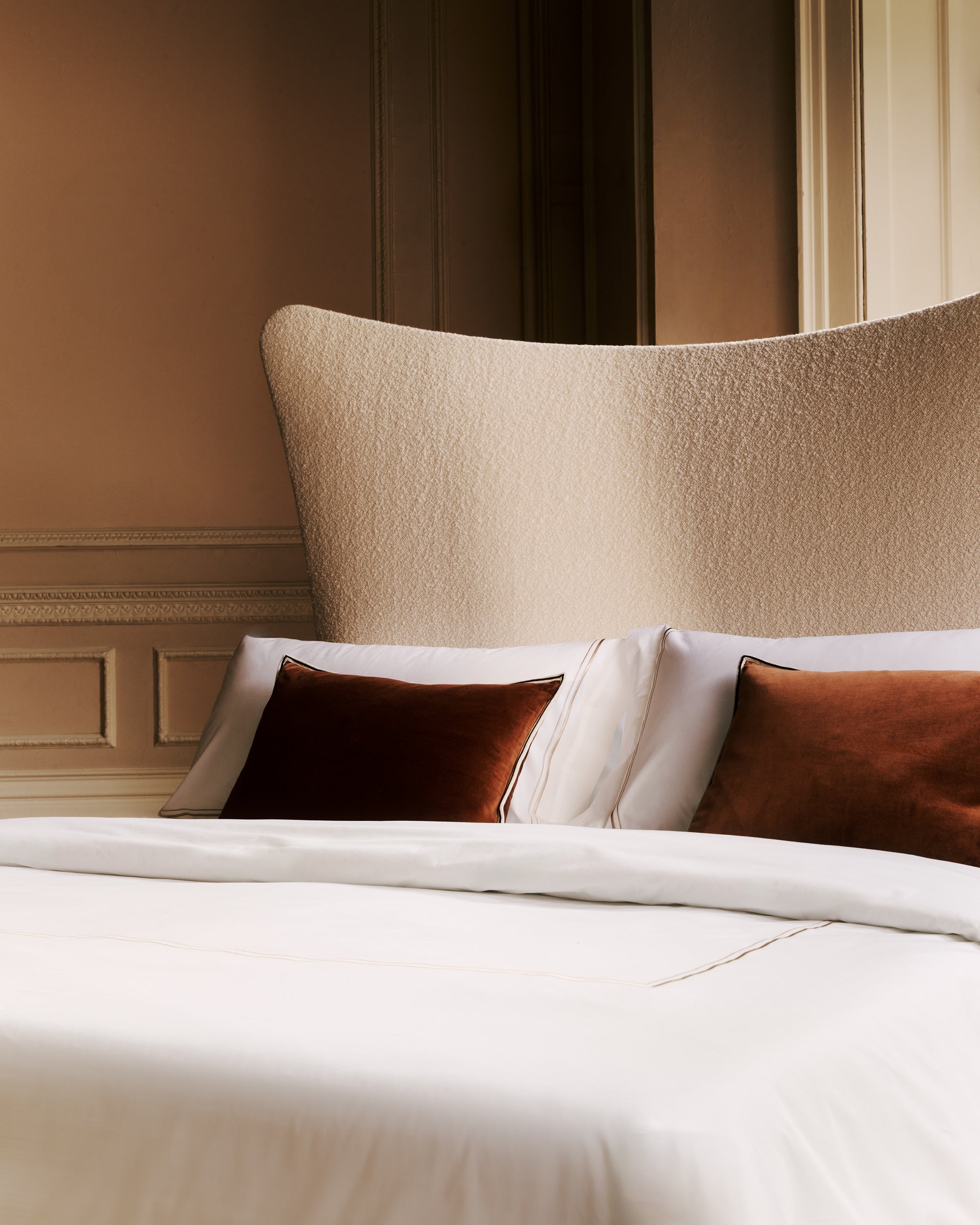 Close-up of the Amelia headboard with pillows and a textured headboard in a bedroom setting.