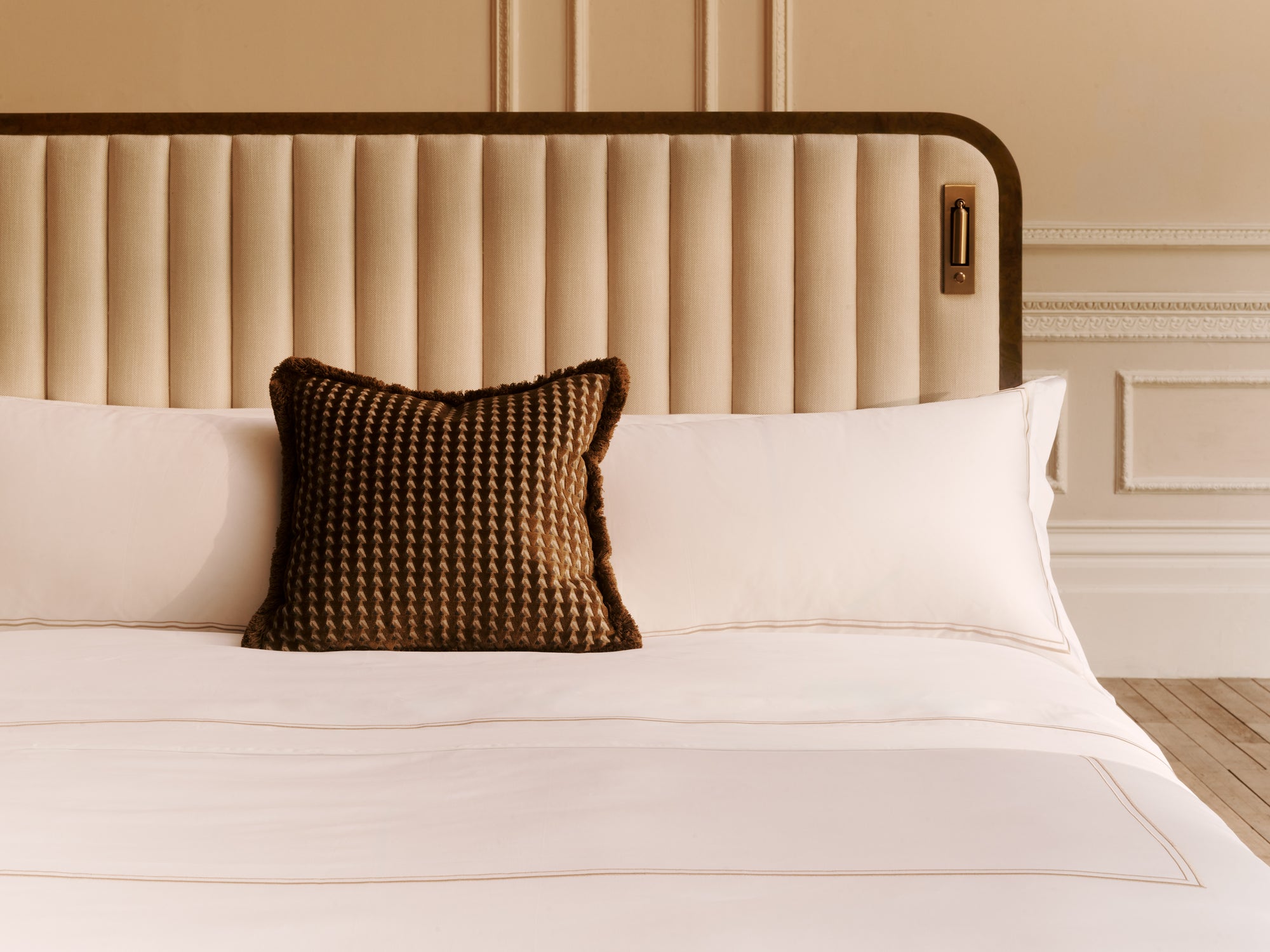 The Luna bed with white bedding and a brown textured pillow against a beige headboard.