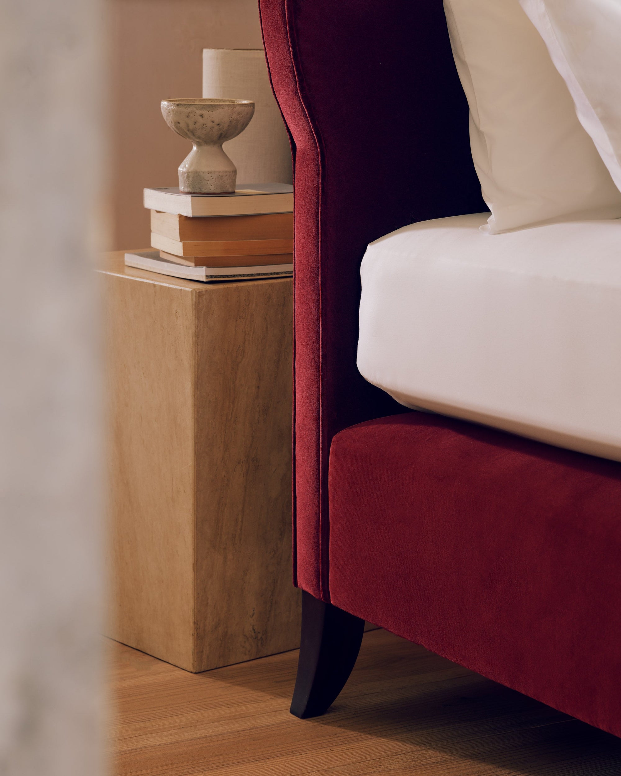 Close-up of the Elly headboard and Savoir mattress, with a leg in Rosewood finish.