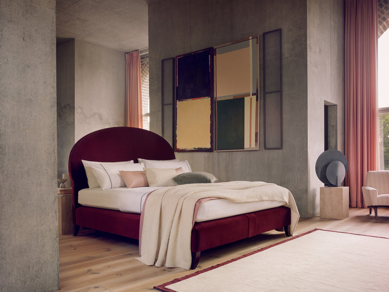 Savoir Elly bed with burgundy headboard and base completely dressed and set in a room