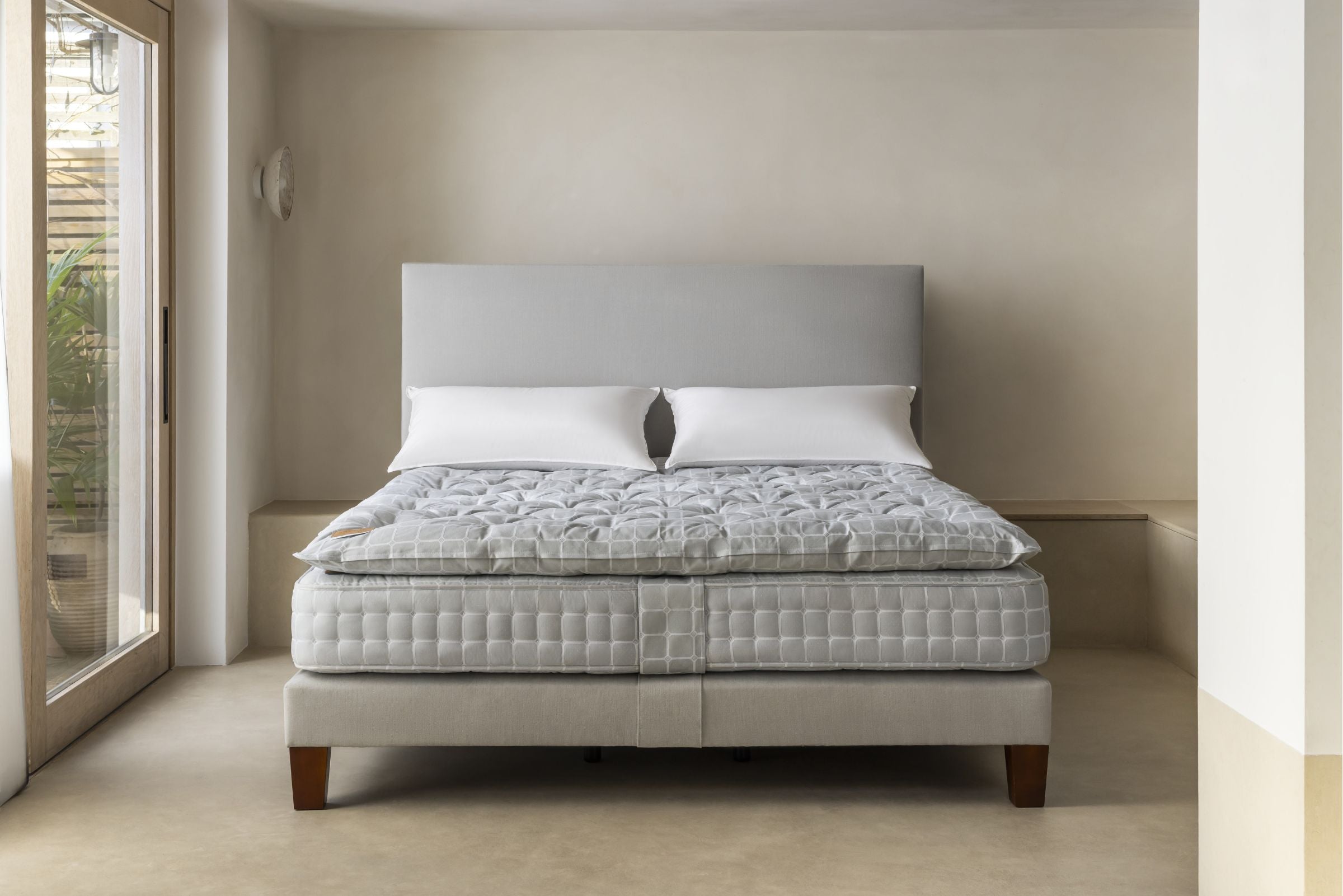 Gray upholstered bed with a Savoir mattress in a minimalistic bedroom.