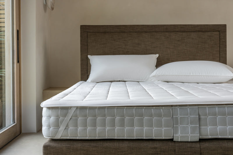Luxury wool mattress protector secured to a Savoir mattress with elastic strap