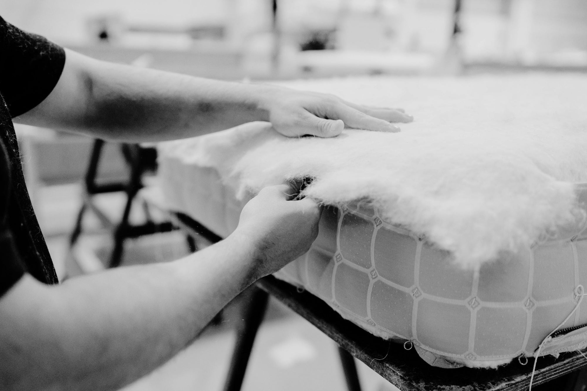 A craftsman is adding natural material into a mattress